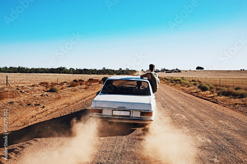 3 guys on a road trip along a Rural dirt road in the desert. © Felix