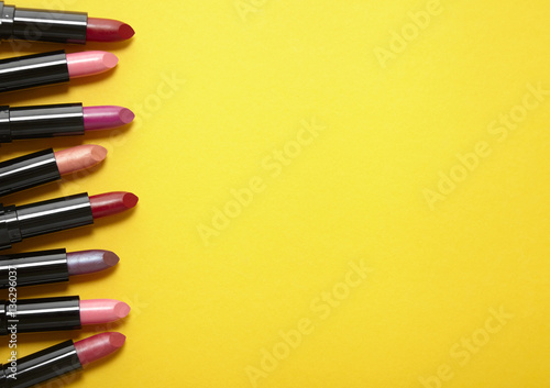 A variety of lipstick make up arranged on a bright yellow background with blank space at side