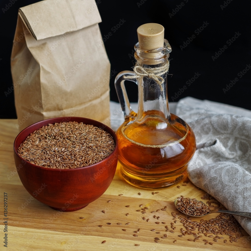 Flax seeds on spoon and in wooden bowl. Linseed oil in glass jug Flax seeds on spoon and in wooden bowl. Linseed oil in glass jug