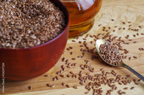 Flax seeds on spoon and in wooden bowl on wooden cutting board