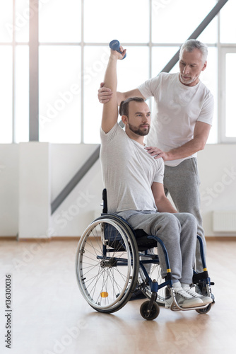 Athletic disabled man training with the coach in the gym