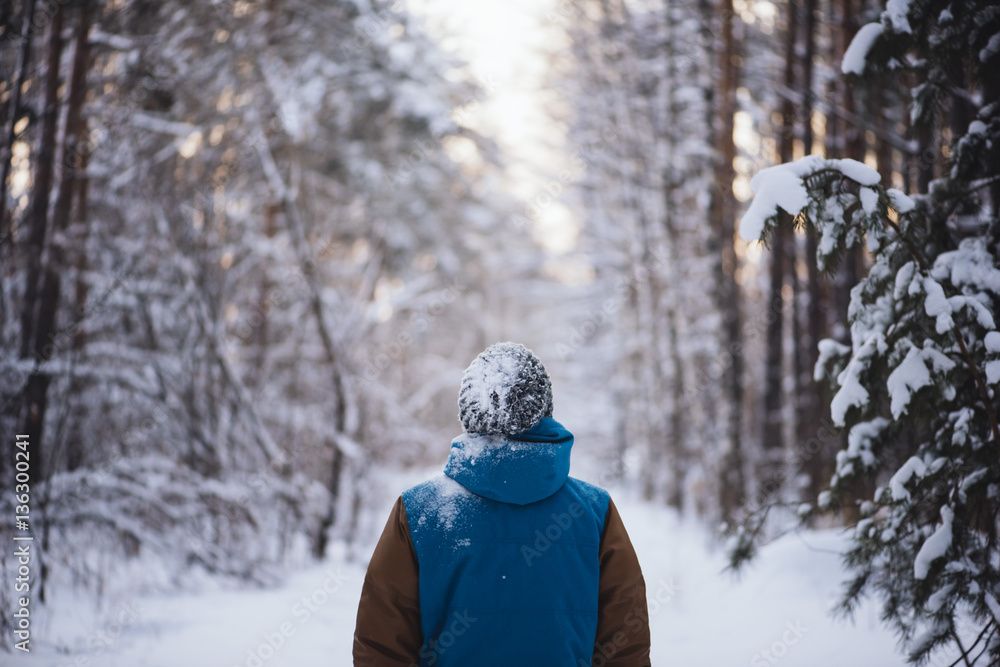 Young man standing all alone in the winter snowy forest Young man standing all alone in the winter snowy forest