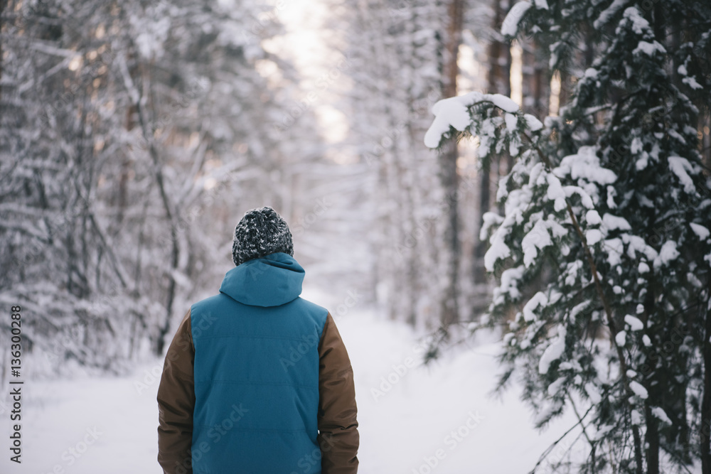Young man standing all alone in the winter snowy forest Young man standing all alone in the winter snowy forest
