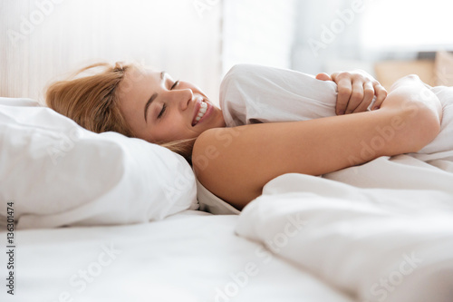 Side view of smiling woman emracing with pillow