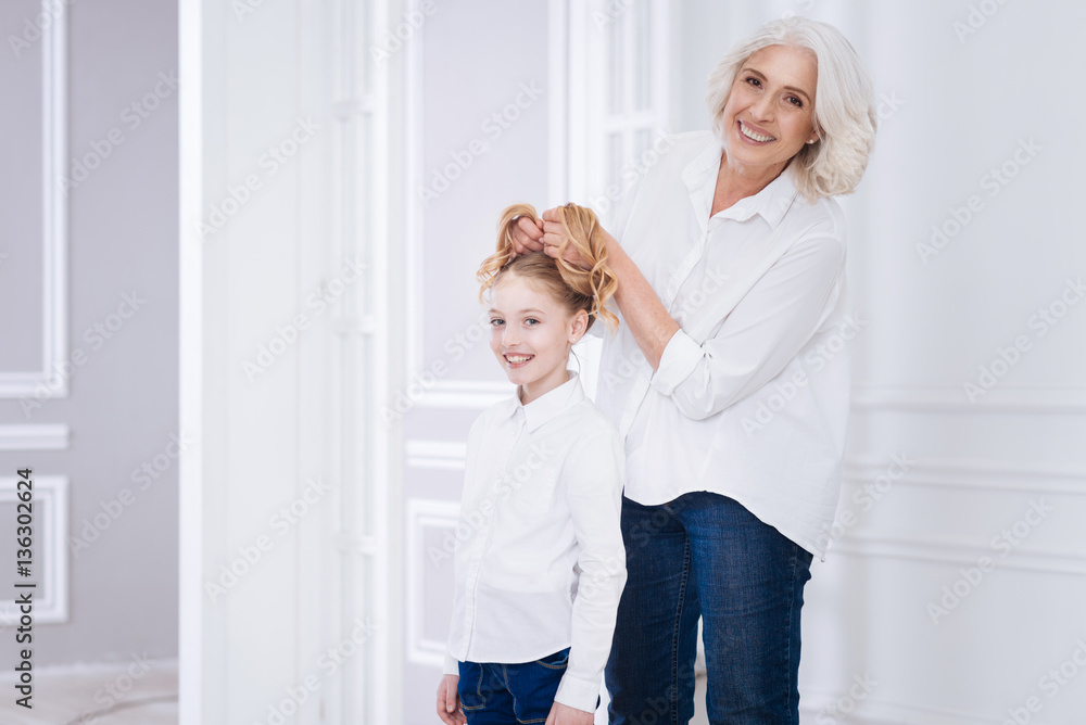 Fototapeta premium Positive content aged woman playing with her granddaughter