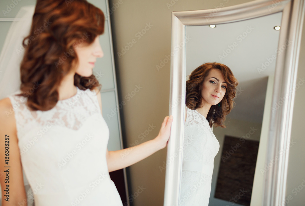 The bride looks at mirror in the room The bride looks at mirror in the room