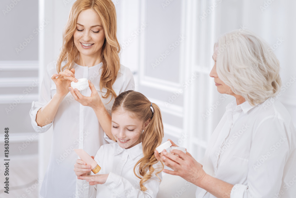 Joyful smiling family members using cosmetics