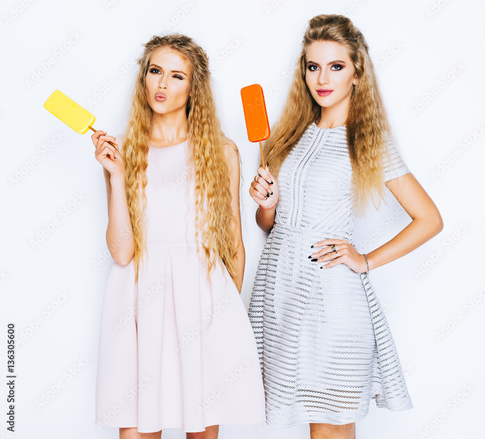 Two best friends having ice cream together indoor on yellow background. Close up of young women eating ice cream and having fun. Eskimo pie. Two best friends having ice cream together indoor on yellow background. Close up of young women eating ice cream and having fun. Eskimo pie.