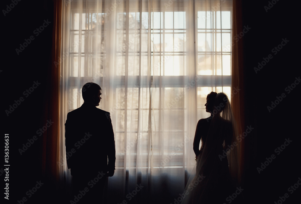 young couple standing on the background of window