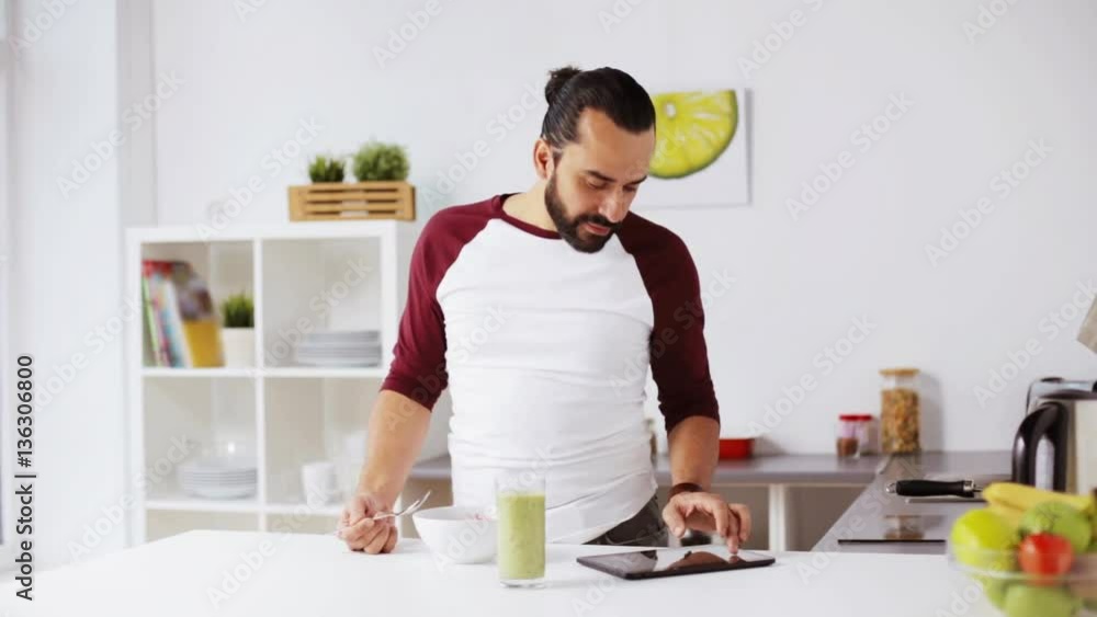 man with tablet pc eating breakfast at home man with tablet pc eating breakfast at home