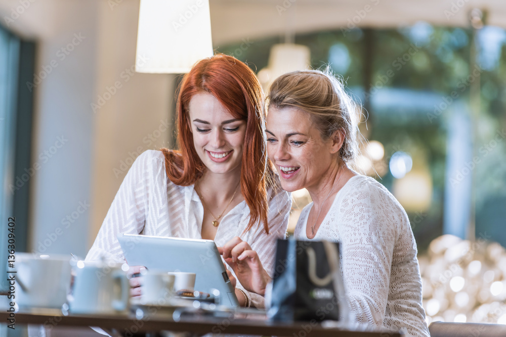 mother and daughter sit in a cafe make the sales on a tablet mother and daughter sit in a cafe make the sales on a tablet
