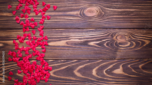 Many little hearts on wooden background.