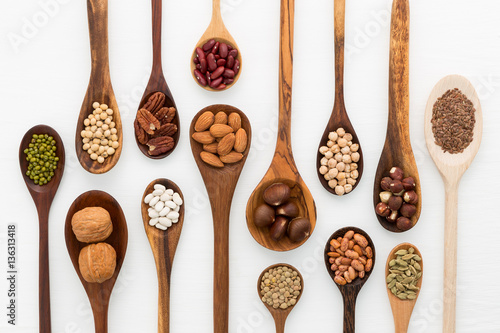 Different kind of beans and lentils in wooden spoon on white woo