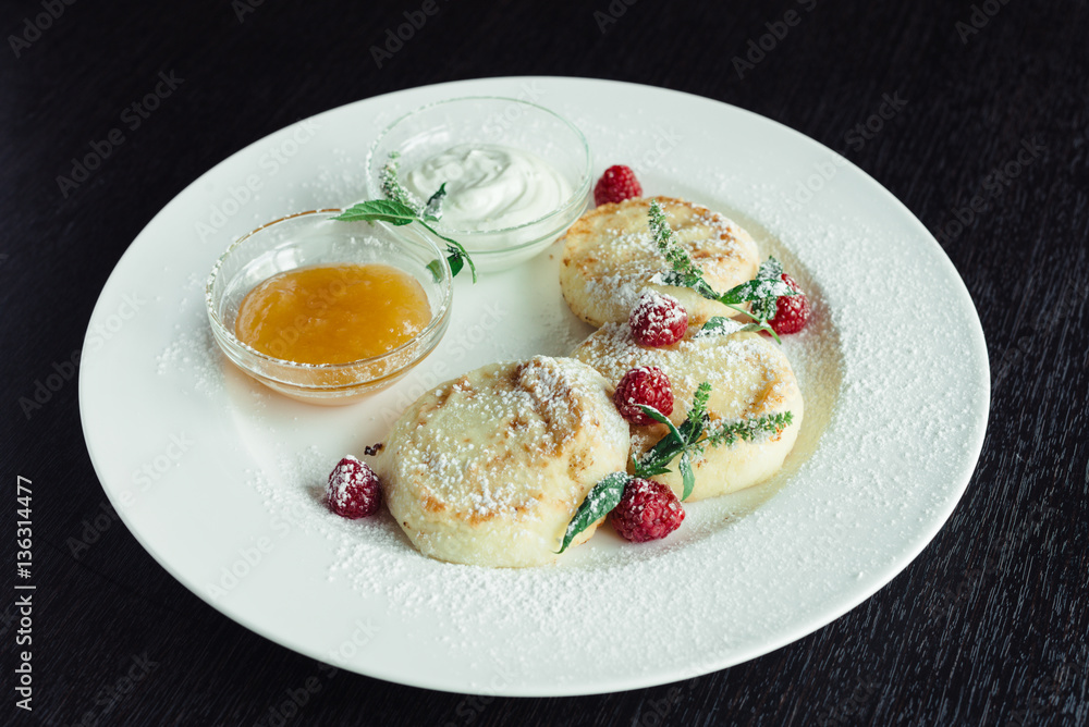 cheese pancakes with raspberries and honey on a white plate on a wooden table cheese pancakes with raspberries and honey on a white plate on a wooden table