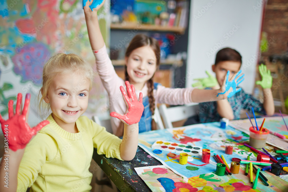 Fototapeta premium Cute girl and her friends with paint on palms