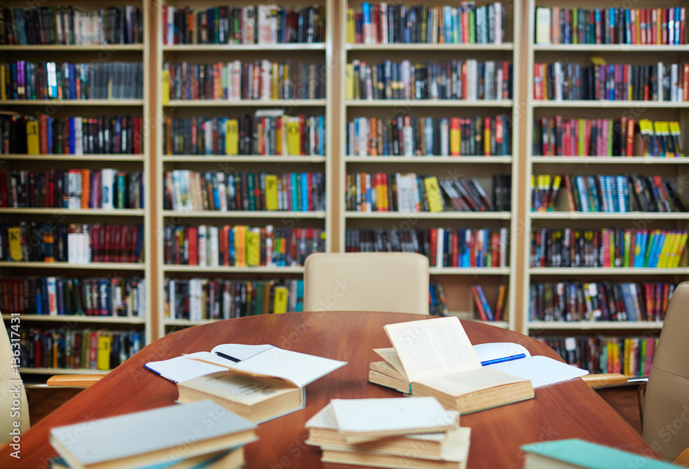 Empty library with bookshelves, desk, some open books and copybooks