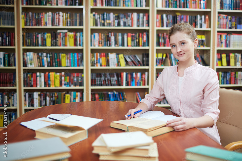Happy girl looking at camera while working in library Happy girl looking at camera while working in library
