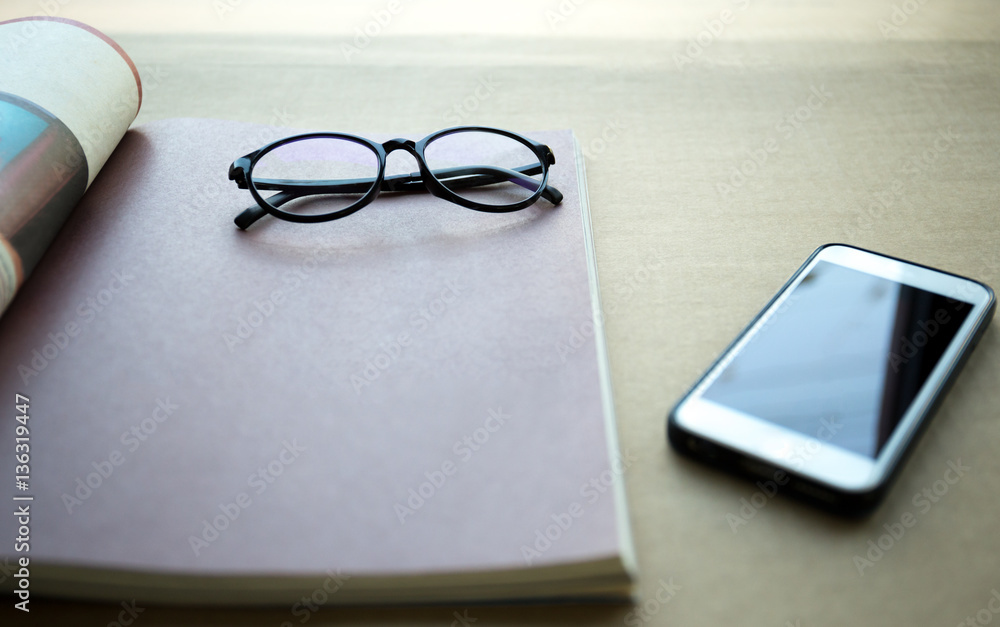 Focus on glasses with cell phone and book Focus on glasses with cell phone and book