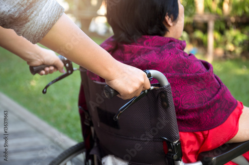 Caretaker pushing senior woman in wheel chair