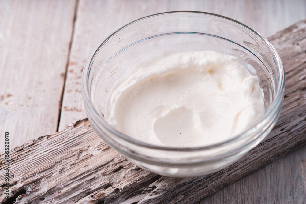 Natural yogurt in the glass bowl on the white wooden background horizontal Natural yogurt in the glass bowl on the white wooden background horizontal