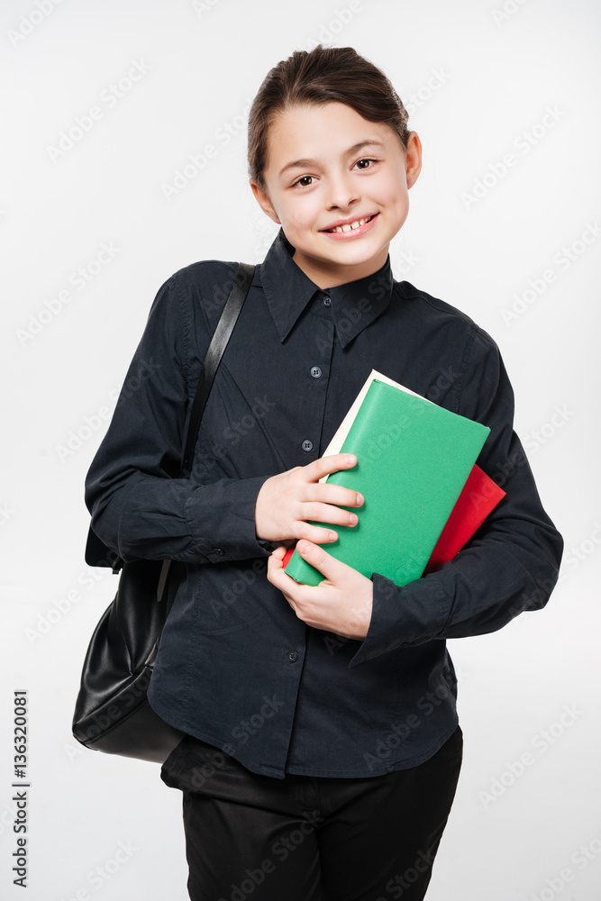 Happy young girl wearing backpack holding books Happy young girl wearing backpack holding books