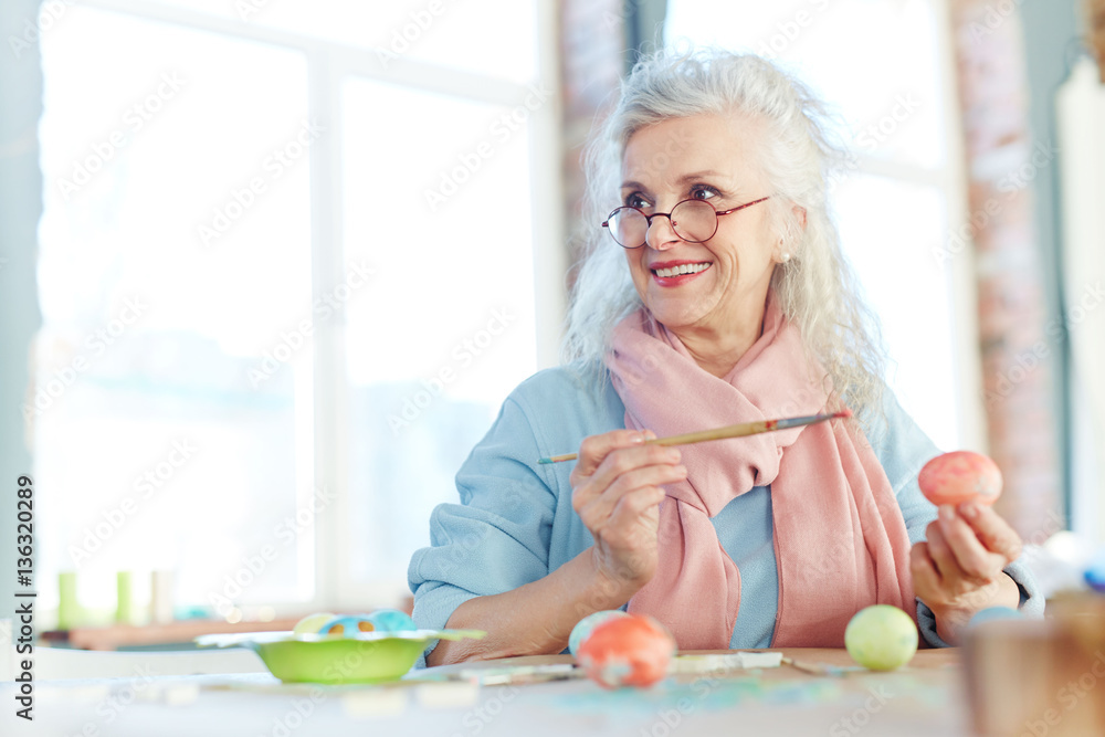 Attractive senior woman painting Easter eggs at home Attractive senior woman painting Easter eggs at home
