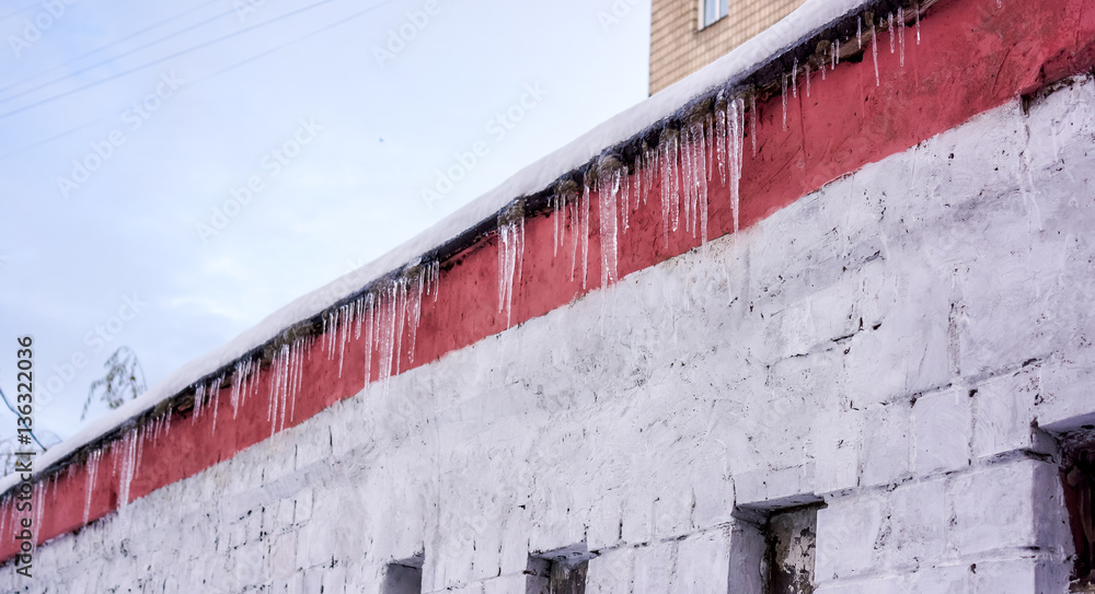 Winter hanging icicles on the house roof Winter hanging icicles on the house roof