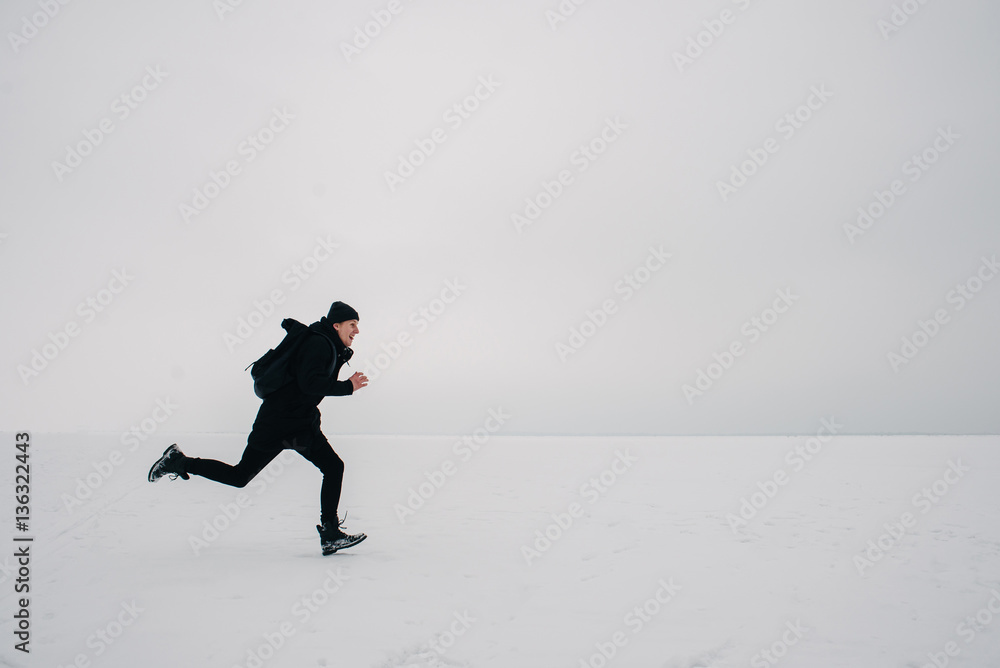 a young man in a black backpack and traveling on the frozen pond a young man in a black backpack and traveling on the frozen pond