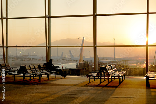 Passenger sitting in a lobby airport waiting for flight in silho