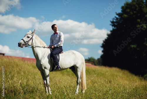 beautiful young groom riding a horse
