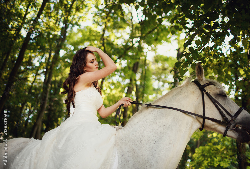 romantic bride riding a horse in the woods