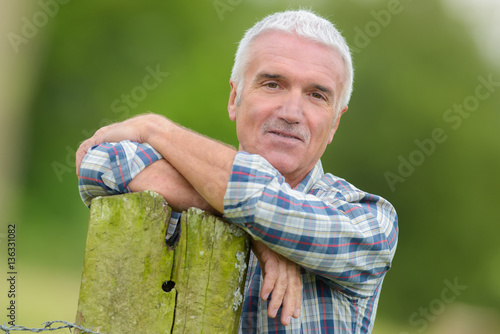 mature man leaning on post