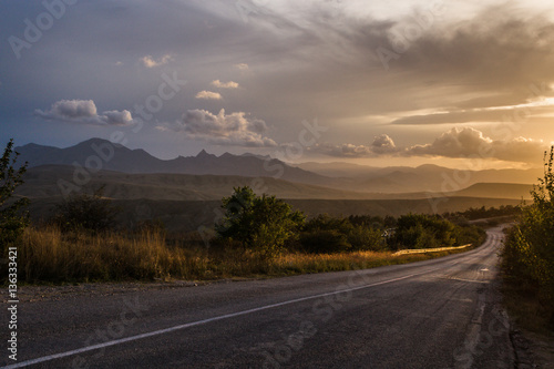 The road in the mountains. Clouds in the sunset.