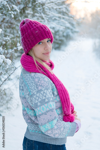 Portrait of young girl in pink hat and scarf in the winter fores