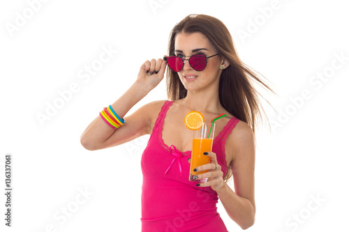 attractive young girl in pink shirt and sunglasses drink orange cocktail isolated on white background