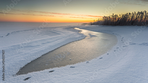 Winter landscape at frozen bay of Puck. Warm light of sunrise early morning. Poland.