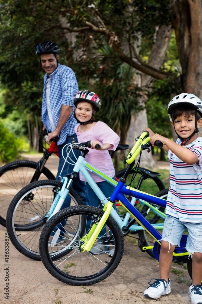 Fototapeta premium Father and children standing with bicycle in park
