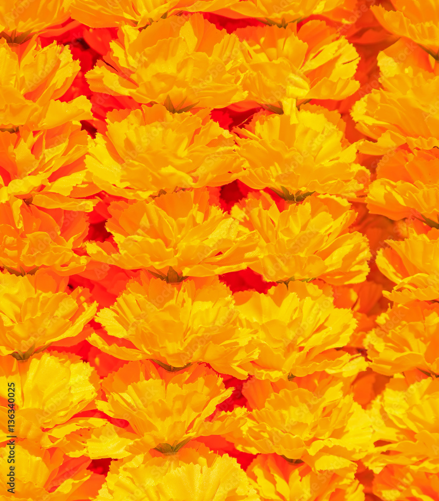 Orange artificial flowers arranged in rows background/texture