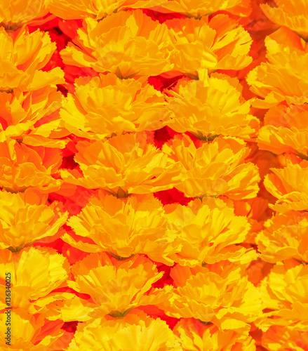 Orange artificial flowers arranged in rows background texture