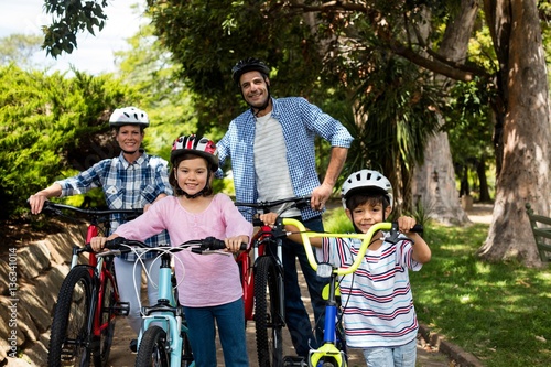 Portrait of parents and children standing with bicycle in park
