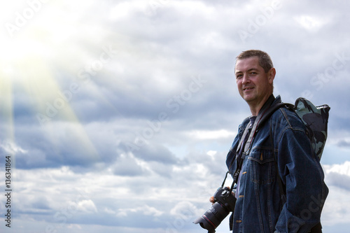 Positive professional photographer on the background of blue sky