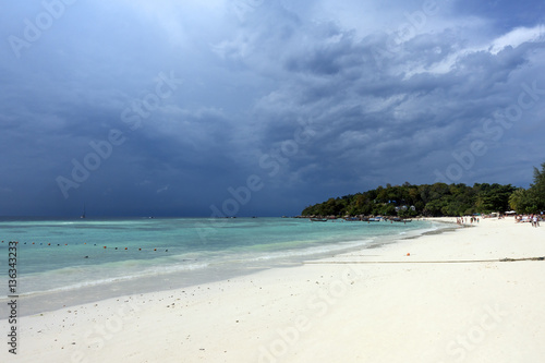 White sandy beach on stormy sky background