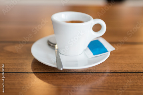 Espresso cup served on a plate with sugar and spoon.