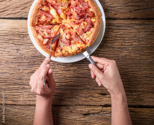 Cutting a delicious Italian pizza with cheese, mushrooms, artich