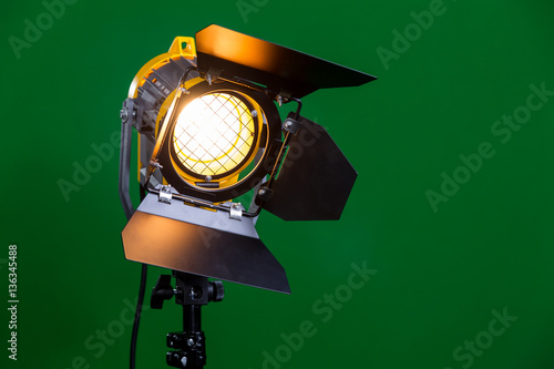 Halogen spotlight with a Fresnel lens on green background close-up.