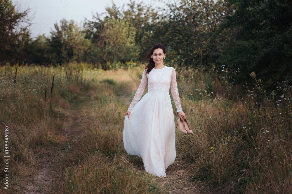 Yong bride spinning in a white dress on the bank on nature.Dress develops in the wind. Happy bride in a wedding dress is spinning.