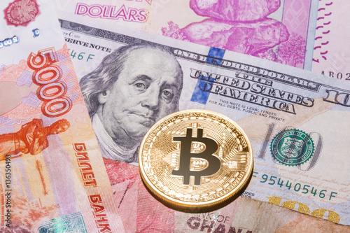 One Bitcoin on multicurrency banknotes. photo