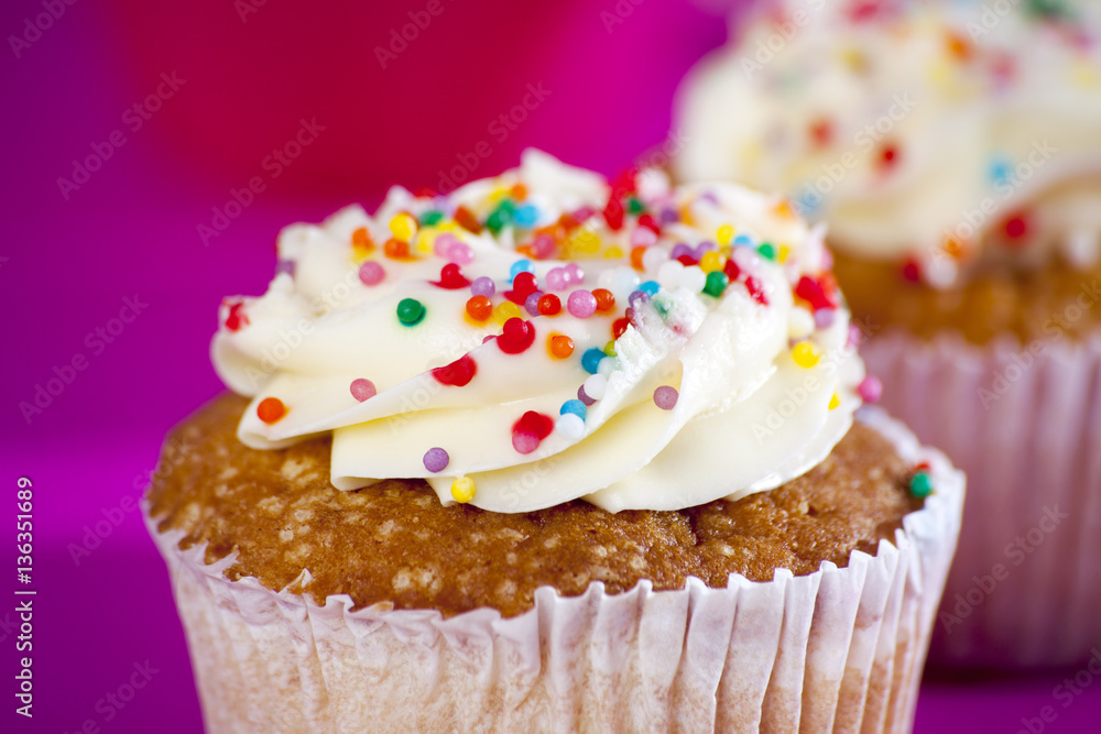 Cupcakes with white cream on the pink background,
