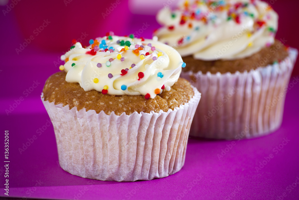 Cupcakes with white cream on the pink background,