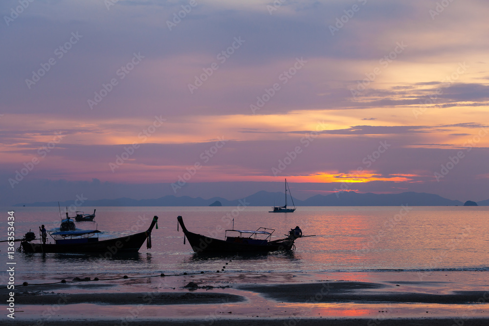 Sunset at Phra Nang Beach, Krabi, Thailand. Typical boat Longtail on a background of smoky islands - rocks and sea in sunset colors